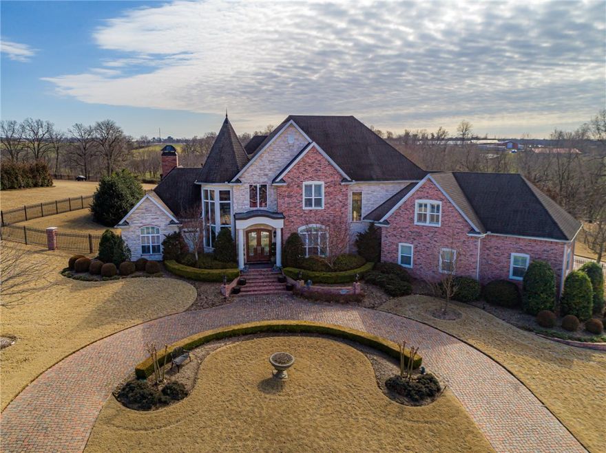 Look at All the Photos This Beautiful Home on lovely 1.92 acres.Custom brick driveways, 1 circle & 1 through gate to rear-load 3-car garage.See the incredible floating staircase, amazing trim-work & floor-to-ceiling windows for light & bright spaces.Wood plantation shutters for privacy on all windows & lovely marble, hardwood & tile floors add to the elegance of the home.Beautiful gourmet kitchen w/top-of-the-line stainless appliances, double wall ovens, double dishwashers, warmer drawer & granite counter-tops. Spacious open kitchen, dining area and large family room makes this a fantastic place to spend time. The large patio, featuring double koi-pond water features can be accessed from the dining area, the living room and the master suite. Master suite is located on the main floor with spacious master bath and his & her walk-in closets.3 large bedrooms upstairs with walk-in closets & 3 baths.Large bonus room & exercise room.All only mins to Walmart home office or U of A.