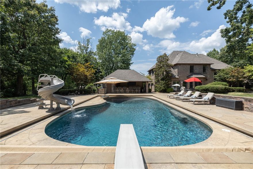 Beautiful home offering spacious living & elegant entertaining spaces inside & out. A circular drive & landscaped grounds lead to a stone & brick exterior with a new roof in 2020. Inside, a two-story entry opens to a living room with stone gas fireplace, formal dining, & kitchen with quartzite countertops, stainless appliances, & walk-in pantry. Kitchen flows into a family room with a second fireplace, creating a comfortable gathering space. Main-level primary suite offers two walk-in closets, jetted tub, & walk-in shower. Upstairs, three bedrooms & a large bonus room have access to two shared full baths, with the bonus featuring a wet bar with sink, icemaker, & refrigerator. Step outside to a heated saltwater pool, multiple patios for lounging or dining, & an open-air cabana-style pool house with huge bar, fireplace, & outdoor kitchen. Garage includes a 50A plug for EV charging. Situated in the gated community of Clear Creek, offering private security & an outstanding Fayetteville location.