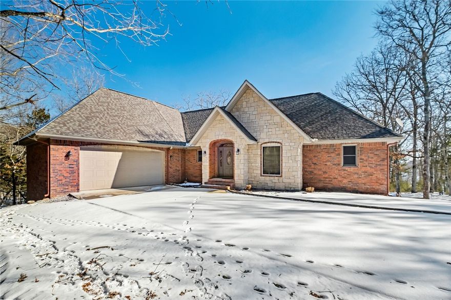 Peaceful, secluded setting, easy walk to the shoreline, and a private dock! Are you ready to enjoy the peace and quiet of natural surroundings and a seasonal view of Beaver Lake? The appeal of this home begins with the brick and masonry exterior and paved parking in front of the two-car garage. Upon entering the home you are welcomed into an open floor plan with the privacy of the primary suite and guest bedrooms on separate sides of the home. The walkout basement has an additional cozy living area that includes a dining table and a wet bar, two bedrooms, a bathroom, and an insulated storage garage for your lake toys. Take a stroll from the patio and backyard down the path to the Corp land to access the private boat dock. Two slips, a swim platform, 2 jet ski lifts, and storage lockers are ready for your lake adventures. Additional features include underground utilities with power to the dock, RV or trailer parking, a fenced back yard, and an additional storage area above the garage.