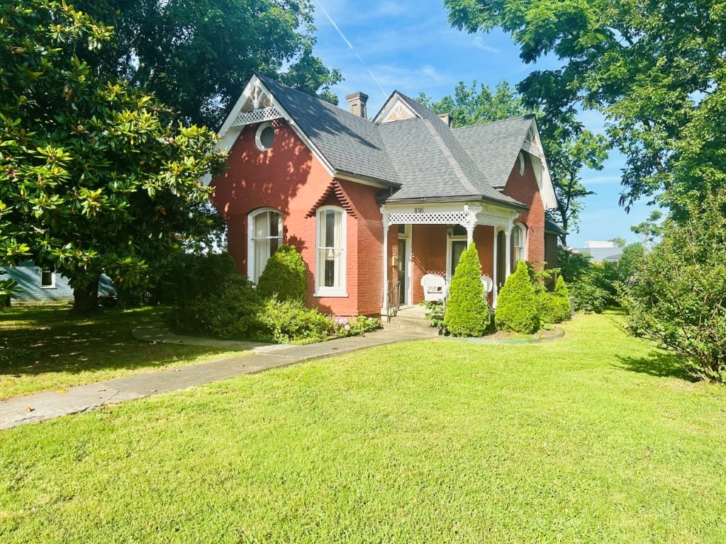 Unique Historical Home in the Heart of Downtown Rogers! Home is listed on the Arkansas Historic Preservation Program. Home features an upstairs bedroom with a half bathroom & plenty of storage area. The downstairs parlor can be another large bedroom on the main floor with another drop-down bedroom in the back of the home with a private door. The formal dining shows well with high ceilings, new windows with plantation shutters sitting off the large living room, beautifully put! The very high ceilings and large windows and crown molding and the original wood flooring throughout with tile.
Kitchen features cherry cabinets, granite countertops, fridge, gas stove, microwave, showcase cabinets with high ceilings and beautiful crown molding. Landscaped yard front & back with storage building, fenced yard, sidewalks, covered porch. Home sits on almost 1/2 acre with lots of room to expand or subdivide the lot.