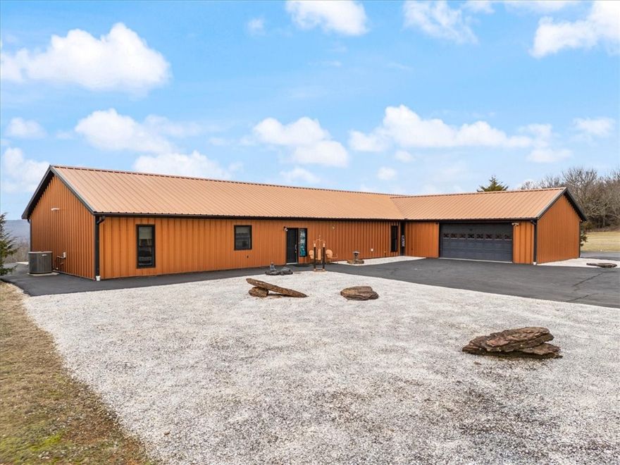 This stunning, handicap-friendly 3-bed, 2 bath home combines rural tranquility
with modern convenience. The open floor plan features a seamless flow between
living and guest areas as well as 3 bonus areas now used as 2 home offices and
exercise room. The primary suite features stunning views and an adjoining sunroom with
a partially sunken hot tub. A spacious mud room/laundry area has access outside
and to a drive through garage and circle drive. Outside are 2 storage areas with
space for tools, equipment, and a workshop. The home has rural water and a large
gas-powered generator if needed. A spacious concrete patio with an expansive wall
of windows, 2 doors and a glass sliding door reveal breathtaking mountain views all
the way to Oklahoma. Scenic paved roads are 22 minutes from a good grocery
store and gas station and 30 minutes from Fayetteville, Arkansas second largest
city. Convenient school bus pickup is at the house. Peaceful living with practical
accessibility beckons.