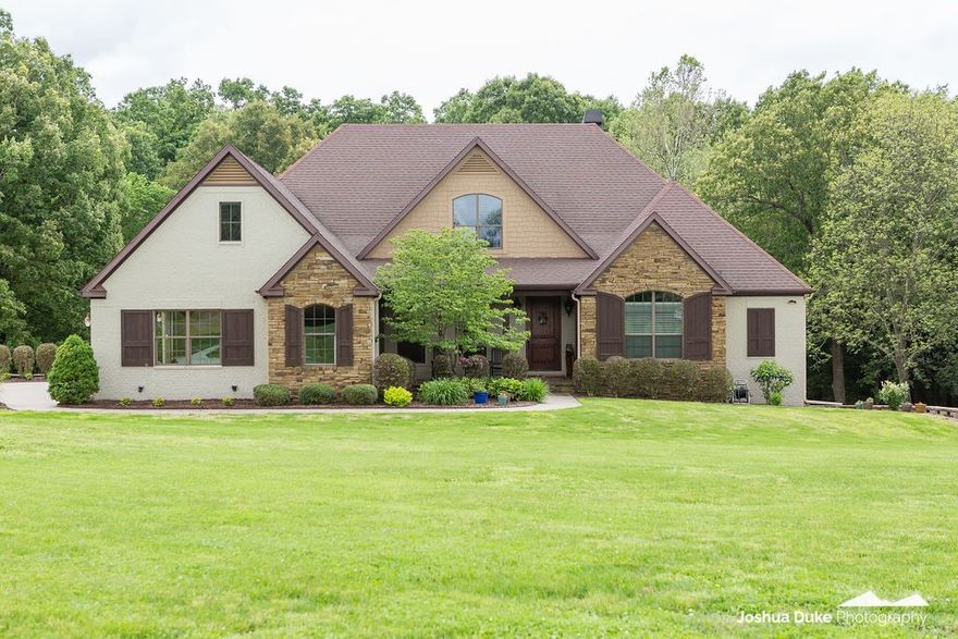 Remarkable property on 7.14 acres with fabulous amenities! Features include 5 Bedrooms 4 Baths, formal dining, sunroom & ¾ inch hand scraped hickory floors. Living room has gas fireplace & large windows giving picturesque views of the woods, pond, & your own backyard paradise. With plenty of space for entertaining, the bright kitchen features two large islands with granite countertops, double ovens, & opens to a cozy hearth room with stacked stone fireplace & french door to the deck. Owner’s Suite includes sitting area, gas fireplace, new carpet & bathroom with whirlpool tub & walk-in shower. Additional bedroom & bath on main level while downstairs you will find a den with wood burning fireplace, kitchenette, three bedrooms, craft room, & two baths. Desirable outdoor features include a new 30x30 shop built in 2019, covered patio & deck, in-ground saltwater pool & professional landscaping. Do not miss this opportunity to own this private retreat just minutes from HWY 112 & I-49.