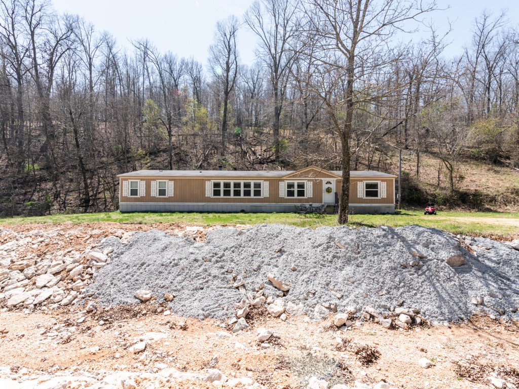A 5 bedroom, 3 bath double wide- Secluded- sitting on 5 acres and walking distance to lake access to Beaver Lake. Only minutes to downtown Rogers. Partially flat acreage-about 2 acres sloped/rolling behind property. Great investment property! Income of $1050 monthly. All electric and Well water. This spacious home has over 2100 square feet- carpet and tile through out. 2 living areas. Occupied- Schedule appts through showing time.