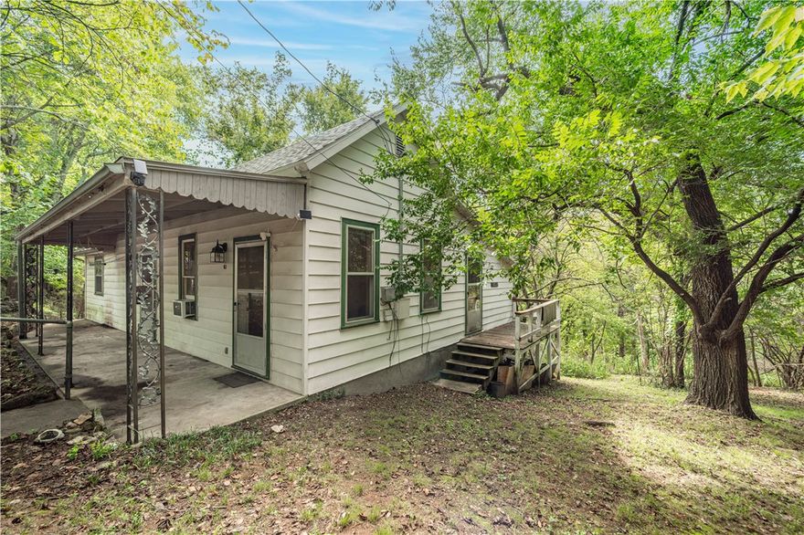 What's your Eureka dream idea?  This cute fixer-upper with hardwood floors was once the Ozarkana Cottage, former home of a well-loved local musician and used as a music store and guitar repair shop.  A real part of Eureka Springs music history!  Zoned Quiet Commercial, this could be a quaint getaway, nightly rental, small cafe, or other business.  Lovely garden spaces as well as your own private hollow teeming with wildlife, berry bushes and native plants.  You will see deer, fox, rabbits, many birds and other wildlife here, right in the middle of town.  Recently surveyed, four city lots are included and building additional cottages or shops is a possibility.  Amazing location just across the street from Bubba's BBQ, Float Eureka Outfitters and Eureka Sweets Bakery.  Arkansas offers a 40% tax credit on approved renovations in Eureka Springs.  The possibilities are here, waiting for your vision.