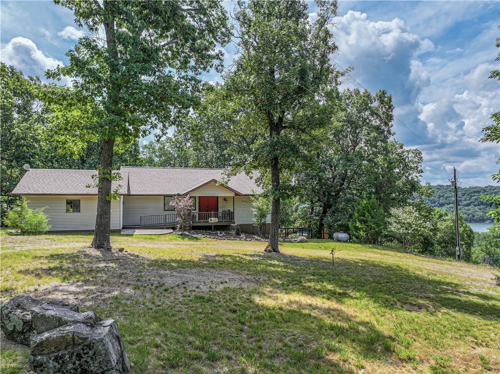 Main level living on the lake! This home is a serene retreat in a desirable neighborhood, with a large living room, large primary bedroom and bath, plus kitchen and washer/dryer all on the main level, with warm wood floors and a covered back deck overlooking the lake. Beautiful wide winter lake view. Full year view potential with a few select tree removals. The lower level has two bedrooms and a bathroom, plus a versatile and cozy den with a pellet stove and a large workshop area (with sink) that is perfect for woodworking, an art studio or an exercise room. The roof is only 1 year old, with impact-resistant shingles. This neighborhood has its own boat ramp. A portion of the backyard is fenced. Thereās a double gate at the front plus a back gate that opens to the rest of the property. A whole-house generator, two car garage, beautifully wooded 1.6 acre lot and circular drive complete this well-priced Beaver Lake home.