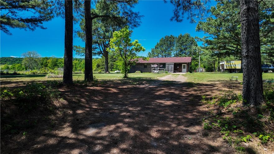 Charming country home situated on approximately 1 acre in the peaceful Center Ridge area! This one-level brick home offers rustic character throughout with warm wood accents, spacious living areas, a cozy fireplace, and a separate laundry room for added convenience. Originally a 3-bedroom home, one bedroom was combined to create an enlarged primary bedroom with additional space and comfort. Recent updates include a roof replacement and installation of a central HVAC system approximately 3 years ago. Enjoy relaxing mornings and evenings from the large covered porch overlooking the scenic rural setting. The property also features an attached storage/work area with concrete flooring, a storage building, concrete driveway, and plenty of outdoor space to enjoy country living while still being conveniently located to surrounding communities.