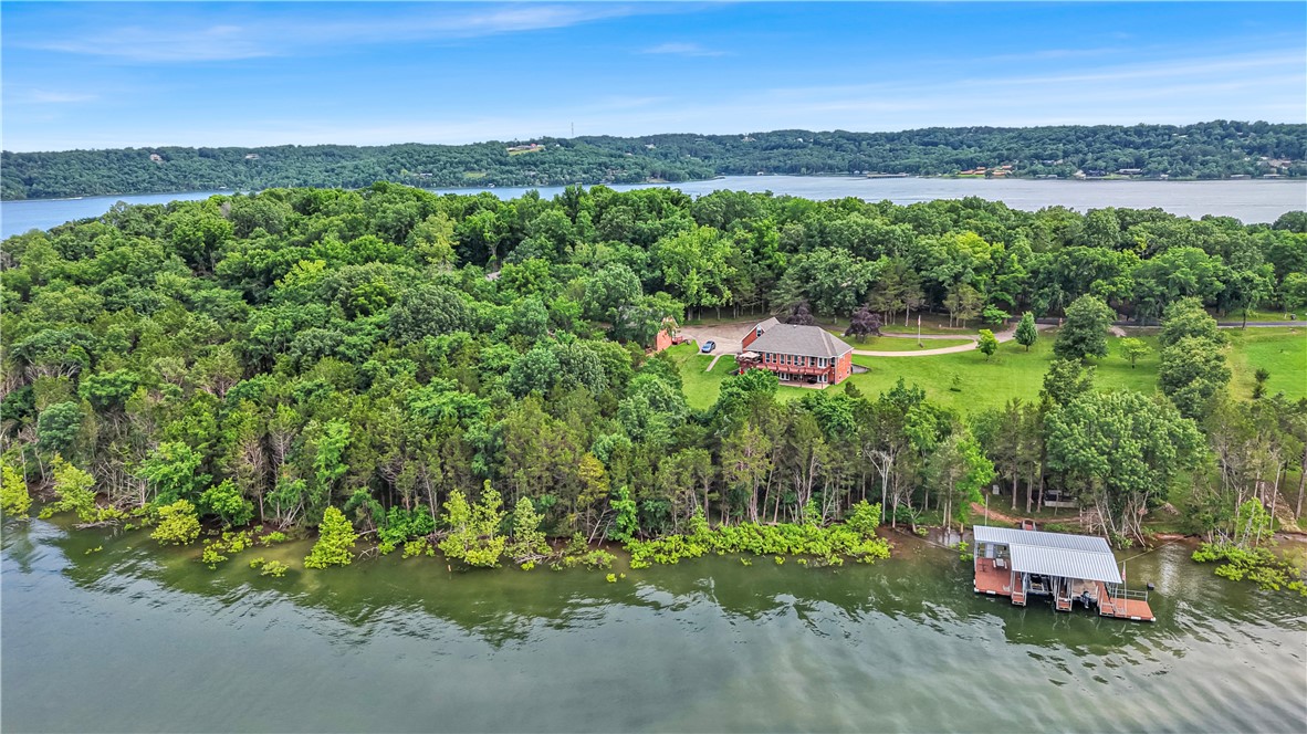 Rare opportunity in Ventris Point—one of Beaver Lake’s most coveted deep-water coves. This 2-story home sits on over 3 acres with 5 garage bays (attached & detached), engineered for durability & thoughtful design. Inside, you'll find vaulted ceilings, granite counters, solar shades, and a Generac generator powered by a 1,000-gallon buried propane tank. The garage workshop features expansive storage & 2 separate bonus rooms. Effortless walk to your 30x32 private dock with 2 oversized slips, custom boat lifts, stainless cables, 2 swim platforms, sea anchor, & winches—an increasingly rare find. Enjoy the custom treehouse that offers electrical & ceiling fan for fun for all ages. A seperate outbuilding offers a custom powered levy system offering ease of storage. The irrigated garden beds are connected to a lake-fed water source. Usable acreage offers room for future expansion, recreation, or guest quarters. This home awaits as your premium lakefront forever home or the ideal lake house to enjoy seasonally.