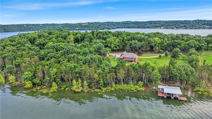 Rare opportunity in Ventris Point—one of Beaver Lake’s most coveted deep-water coves. This 2-story home sits on over 3 acres with 5 garage bays (attached & detached), engineered for durability & thoughtful design. Inside, you'll find vaulted ceilings, granite counters, solar shades, and a Generac generator powered by a 1,000-gallon buried propane tank. The garage workshop features expansive storage & 2 separate bonus rooms. Effortless walk to your 30x32 private dock with 2 oversized slips, custom boat lifts, stainless cables, 2 swim platforms, sea anchor, & winches—an increasingly rare find. Enjoy the custom treehouse that offers electrical & ceiling fan for fun for all ages. A seperate outbuilding offers a custom powered levy system offering ease of storage. The irrigated garden beds are connected to a lake-fed water source. Usable acreage offers room for future expansion, recreation, or guest quarters. This home awaits as your premium lakefront forever home or the ideal lake house to enjoy seasonally.