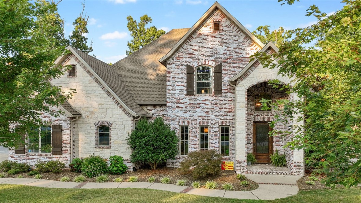 This private, wooded acre in Versailles is perfect for gathering loved ones—just minutes from downtown Bentonville and Walmart HQ. Inside, light-filled, open spaces make life easy. The chef’s kitchen, with granite countertops, dual sinks, stainless appliances, and a 36” pro gas range, anchors the home. The main-floor primary suite offers a walk-in shower, jetted tub, dual vanities, and a closet connected to the laundry. Also on the main level: a formal dining room, office, half bath, three-car garage, and inviting living room with beams, brick, and fireplace. Upstairs, three bedrooms with walk-ins, two baths, and a media room with projector and kitchenette await movie nights and sleepovers. Outside, enjoy a covered patio with grill, pool with waterfall, and lush landscaping. An expanded driveway offers plenty of parking for family and friends.