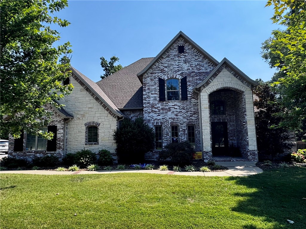 This custom brick-and-stone home sits on a private, wooded acre in the sought-after Versailles subdivisionājust a few miles from downtown Bentonville & Walmart headquarters. Inside, the spaces are open & functional, with natural light pouring through expansive windows. The chefās kitchen & breakfast area are a focal point, featuring granite countertops, dual sinks, stainless steel appliances & a 36ā pro gas range. The main-floor primary suite offers expansive windows, a walk-in shower, jetted tub, dual vanities, and a large closet connected to the laundry room. A formal dining room, office, half bath, three-car garage, and open living space with exposed beams, brick, and a gas fireplace complete the main level. Upstairs, youāll find three bedrooms with walk-in closets, two baths, and a media room with a projector and kitchenette. Outside, enjoy a covered patio with a built-in grill, a sparkling pool with a waterfall and stamped concrete surround, an expanded driveway with ample parking, and lush, mature landscaping
