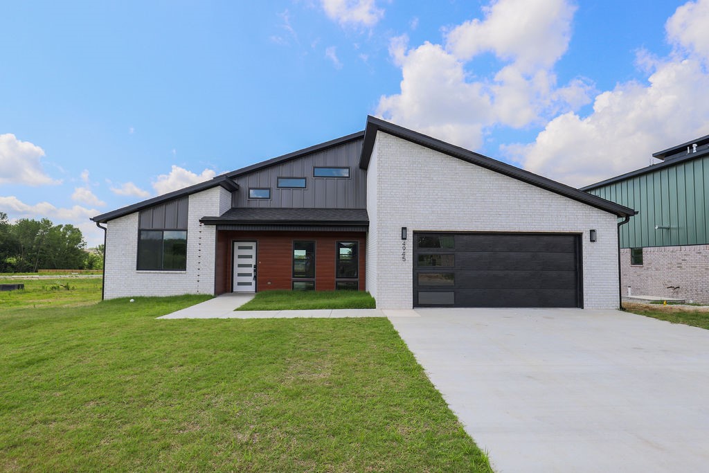 This stunning new construction home is built for modern living. This brand-new residence showcases beautiful brick exterior with maintenance-free metal siding and garage door featuring a stylish window. The welcoming front entrance boasts glass panels for natural light and convenient keyless entry. Inside, luxury vinyl plank flooring flows throughout, complemented by custom cabinetry with quartz countertops and a distinctive butcher block island. Upgraded smart appliances include a pot filler and built-in microwave, while the thoughtful mudroom provides practical storage. The garage features epoxied floors and EV charging capability. Cathedral ceilings create spaciousness, enhanced by LED lighting and mid-century modern fixtures. The master suite includes a walk-in closet and spa-like bathroom with fully tiled shower. Additional highlights include a walk-in pantry, laundry room with butcher block counter, covered back patio with epoxy flooring, ceiling fan, and smart mirrors with adjustable lighting throughout.