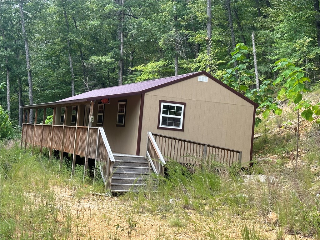 End of the road privacy privacy with under ground electric and rural water in place at the driveway. 7.64 acres of large hardwoods, 2 year round springs, seasonal creek runs along the southern boundary of the property. 16x52 very well built cabin that is in the dry and just waiting to be finished out to your desires, septic tank already installed. Covered porch runs the full length of the cabin to relax on and enjoy the sights and sounds of the forest surrounding you. All only a short drive to the Buffalo River, Jasper, or Harrison.