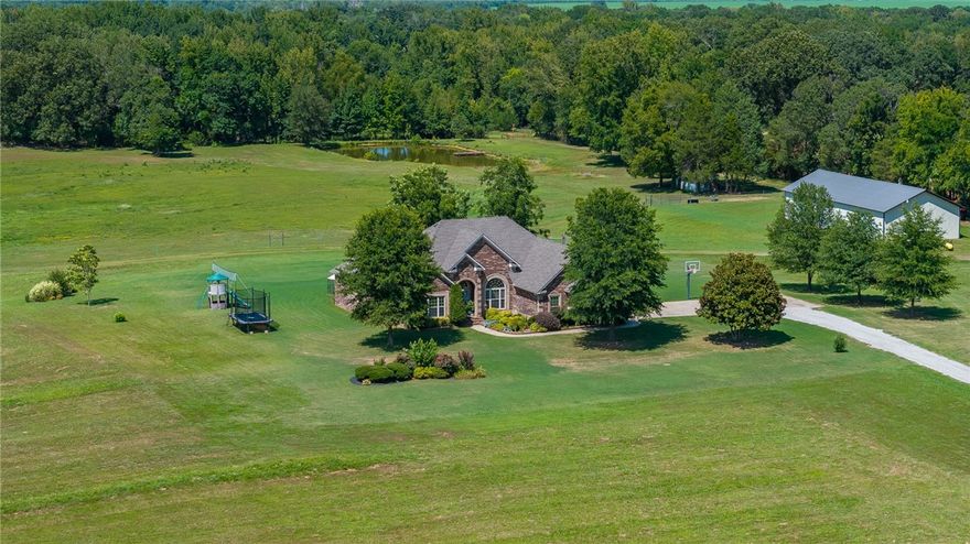 Nestled on 18.58 acres, this exceptional property offers both luxury and functionality. Step inside to find travertine and hardwood floors, detailed with elegant crown molding. The spacious kitchen is equipped with stainless steel appliances, pull-out drawers, and a refrigerator that will stay. Relax in the bonus sunroom or work from home in the dedicated office space. Outdoors, enjoy a private pond with a dock, along with a covered entertainment area complete with a wood-burning fireplace, perfect for gatherings. The property is fenced for horses and cattle and includes a 30 x 80 shop with water, electric, and 12’ walls. Professionally landscaped with a sprinkler system, the grounds are as beautiful as they are expansive. Additional highlights include a brand new HVAC system installed in 2024, a roof replaced in 2023, and a fully wired sound and security system. This home truly has it all.