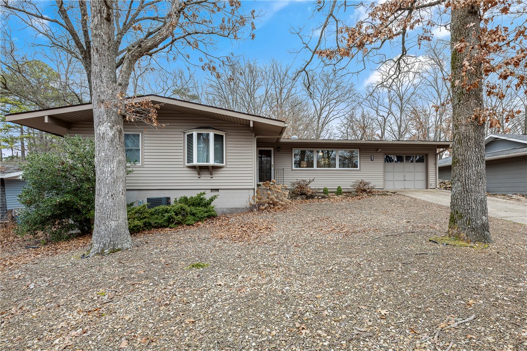 Discover a REMARKABLY UPDATES Mid-Century Modern charm in this Bella Vista home! The spacious, open living area features a striking stone wood-burning fireplace. A modern kitchen boasts a large island, sleek fixtures, and quartz countertops. The primary bath is a spa-like retreat with a soaking tub and separate shower. Offering 3 bedrooms, an office, and 2.5 baths, this home also includes a sunroom with peaceful views of the flat, wooded backyard and a heated office with a mini-split for year-round comfort. Enjoy upgrades like high-efficiency HVAC, Anderson windows, Pergo laminate flooring, and a new mini-split. The backyard storage building serves as a versatile workshop. Please note, the home is on a 2-bedroom septic system. Seller will provide a new modern garage door with an acceptable offer!