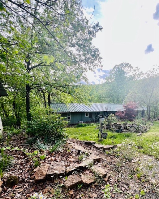 The perfect NW Ar. serene nature retreat can be your home away from home nestled in the woods. Sitting on 2.98 Acres, the home is surrounded by beautiful flowers & natural beauty. The home’s stunning kitchen & bath, were recently remodeled. Equipped with a Verona 6 burner gas range w double oven, full size refrig, plus a beverage refrig, a drawer microwave built in the island. The surfaces are lined with granite, tile and wood creating the perfect kitchen w buffet for the adjacent fireside dining area. With 3 fireplaces, a wood stove, native stone hearth, central hvac, 3 split units & a generator, you are set for comfort all year long. Master BR/Bath enjoy a huge walk in shower, double vanity sink. Utility room, office nook and walk in pantry also. The spacious lower level sunroom with fireplace has a shelf lined wall & opens to the back deck outdoor cooking/entertainment. 3 storage buildings function as you like, along with a 2 car carport and shed.