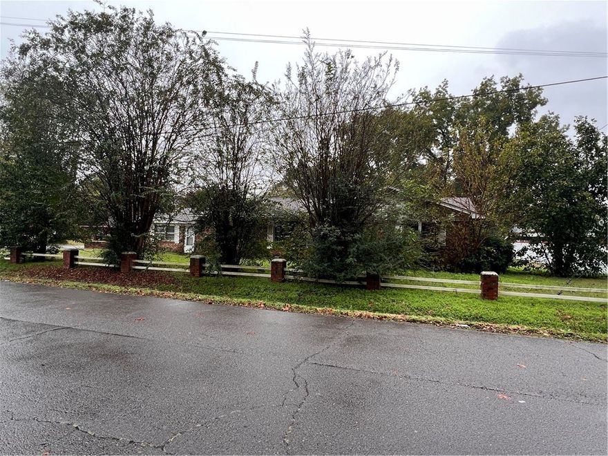 This in-town Dardanelle home features a spacious layout on a large corner lot and offers an opportunity for improvements. The main entrance opens into a large living area with two bedrooms to the right. At the front of the home, an eat-in kitchen leads to stairs that descend into a den with a wood-burning fireplace, along with a nearby half bath and laundry area. A hallway off the den leads to a bonus room on the left and two additional bedrooms on the right, along with an exterior door that opens to the parking area. A large covered patio provides additional outdoor space. With generous square footage and a flexible floor plan, this property presents a chance for a buyer to update and tailor it to personal preferences.