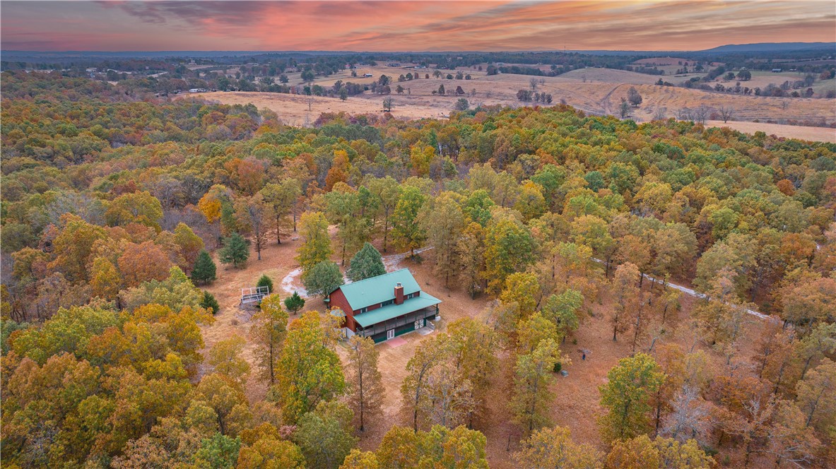 Ask about $1,000 credit utilizing our preferred lender! Discover the perfect blend of luxury and tranquility in this stunning 4bd/4.5ba home, nestled on 8.85 wooded acres. The main level is perfect for entertaining, featuring an open foorplan w/ large living area, wood burning fireplace & 1/2 bath. The kitchen has an eat-in area & a formal dining room. Spacious primary suite, complete with a walk in closet & bath w/ custom tile shower & double sinks on main level. Upstairs, is a library + 2 additional suites, each with its own bathroom + walk-in shower. The lower level features a den, office, bedroom, full bath w/ whirlpool tub & wood burning fireplace. A workshop area, storage room & storm shelter/safe room add practicality. Wine cellar accessible from the exterior & a whole-home generator to ensure peace of mind during any weather. Step outside & enjoy the wraparound porch. 25min to Branson, 35min to Buffalo River, 8min to Harrison city limits.