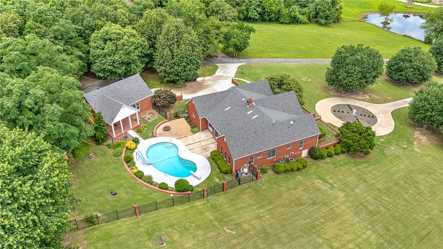 Welcome to your own private oasis in the heart of Fayetteville! This exceptional estate home boasts a rare combination of spacious luxury and seclusion, nestled on 3.43 acres. Enjoy resort-style living with a lovely swimming pool featuring a slide and diving board, accompanied by a charming pool-house complete with a convenient kitchenette, small fridge, and full bathroom. Entertain in style in the inviting dining room or unwind in the gorgeous sunroom, offering gorgeous views of the surrounding landscape. The kitchen is a chef's delight, featuring quartz countertops, double ovens, a gas stovetop, cabinet-style fridge, and a built-in desk for added convenience. Rest easy knowing the entire home is equipped with a whole house generator. There is a heated attached 2-car garage w/ epoxy floors & storage cabinets as well as a detached 2-car garage with additional storage & RV parking and a 50 amp hook-up. Roof is 5 y/o.  1 HVAC replaced in 2022. All windows are are Anderson and only 5 years old