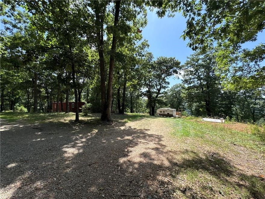 4.9 acres offering privacy close to the end of the road and no restrictions! Property feature electric, rural water, septic, and a new storm shelter (11/2024). Includes a leveled shipping container with door, window, and wood stove. Large pad for camper and a 2020 camping trailer included in the purchase price. Multiple potential build sites and a viewing deck overlooking a finger of the Buffalo River Grand Canyon - endless possibilities  for year dream getaway, build, or retreat.