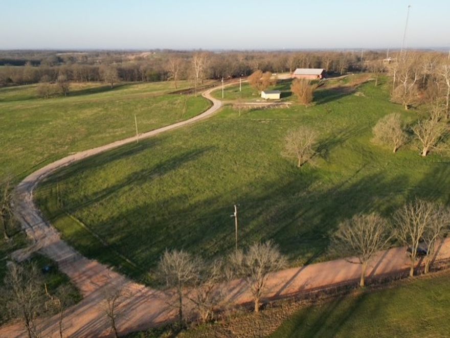 Beautiful 61-acre rolling property fully equipped for livestock operations and ready for your dream home. Features a complete working setup with multiple feedlots, a large covered feeding and vet barn, and a well-designed working corral. Includes a spacious shop with feed storage, plus a stacking shed for grain and bedding. Utilities are in place with an existing septic system, rural water, and electric already set up. Enjoy stunning views from the elevated homesite. Conveniently located just 10 miles from XNA and 20 miles to the Walmart campus, offering the perfect blend of rural functionality and accessibility.