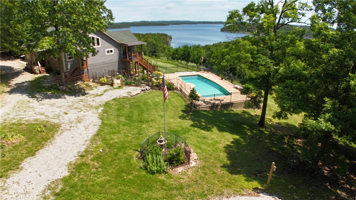 Home with panoramic views of Bull Shoals Lake from almost every room and even while swimming in the salt water inground pool. Beautiful stone fireplace you can see from kitchen and living room. Open floor plan, covered deck overlooking the pool and lake. Kitchen had a makeover in 2022 with custom cabinets and granite countertops along with stainless appliances including ice machine and trash compactor. Eat in bar and separate dining room overlooking the views. Master suite with walk in closet bathroom with double sink vanity and separate tub/shower. Basement has two bedrooms with jack & jill bath just off the family room with wet bar for entertaining. Pole barn for storage and separate building with 1 bed, 1 bath apartment w/efficiency kitchen and shop with 16’ overhead door. RV parking with hookups, fenced back and side yard, circle drive and two car attached garage. All on 4.7 acres mostly wooded. One mile to community airport and half a mile to boat slip in community dock.