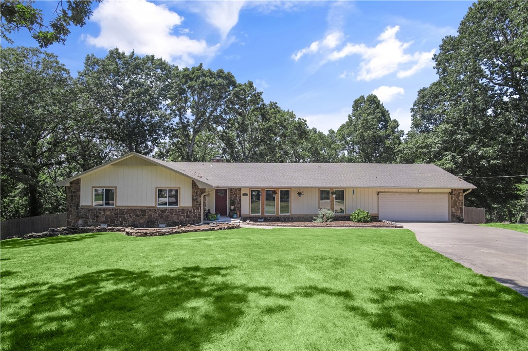 Welcome to this charming and tranquil home located in a quiet neighborhood, with a convenient location to all amenities in Northwest Arkansas. Nestled on a generous lot size of nearly an acre, this property offers scenic and peaceful views. As you step inside, you'll be greeted by vaulted ceilings with beams that add a touch of charm, while the open floor plan creates a contemporary and inviting atmosphere. There is ample natural light through expansive windows. Each bedroom is spacious, and the primary suite provides a peaceful retreat with access to a large deck. This home features updates including a new front porch, windows, doors, paint, light fixtures, flooring, and more. Additionally, the roof was replaced in 2019, and a new HVAC system was installed in 2016. Nature enthusiasts will delight in the abundance of wildlife in the area and seasonal lake views with close proximity to Beaver Lake. This home offers the perfect blend of tranquility, convenience, and natural beauty!