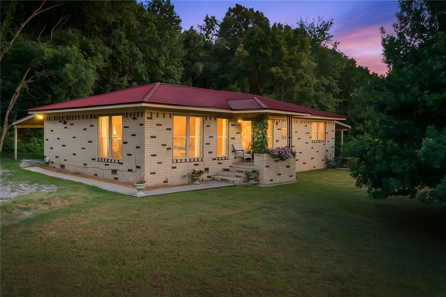 This all-brick home sits on a 0.59 acre hilltop, offering panoramic west-facing Ozark sunset views. Hardwood flooring flows throughout, including bedrooms, the living room , and the dining room. West-facing windows illuminate the master, living, and dining rooms, highlighting the scenic views and filling the home with natural light. The open-concept kitchen, living, and dining areas create a modern feel. A solid wood front door and original, well-maintained tile in both full baths add character and a fun, unique retro touch. Two covered patios offer outdoor living space with shade and views. The covered patio with direct master access and west hilltop views sets the tone for relaxation. Located within walking distance to a school and park, and easily accessible from both 71B and I-49, this home combines tranquility with convenience.