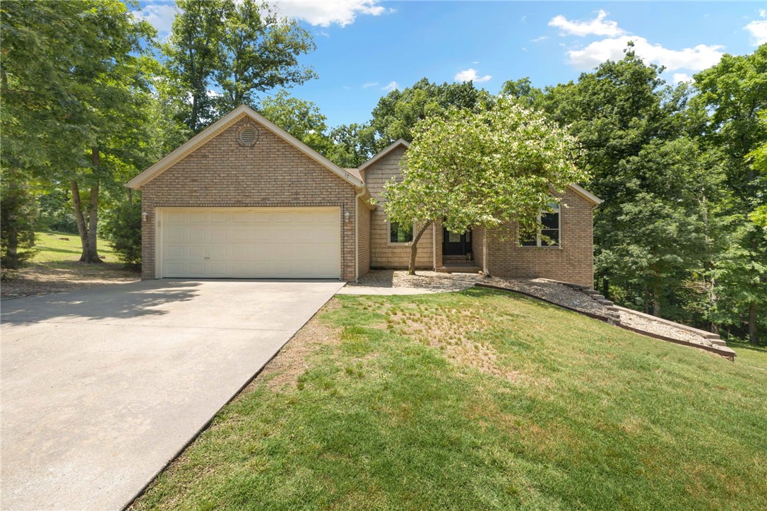 Tucked away in the cul-de-sac and spanning 2 lots, this stunning home offers privacy, space and access to some of Bella Vista's best amenities. Surrounded by mature trees and maintenance free rock landscaping, this property is a nature lover's dream-located just moments from the Back 40 Mountain Bike Trail, minutes from Lake Brittany, and the Metfield Clubhouse-featuring golf, swimming, a fitness center, and a cafe. Step inside to discover thoughtful updates and comfortable elegance. The newer roof ensures peace of mind, while the walk-out basement with bar makes entertaining effortless. Two decks offer the perfect spot for morning coffee or evening relaxation. The primary suite offers private deck access and en suite bath with an oversized walk-in tiled shower. Whether you're looking for outdoor adventure or tranquil seclusion, this home delivers the best of both worlds.