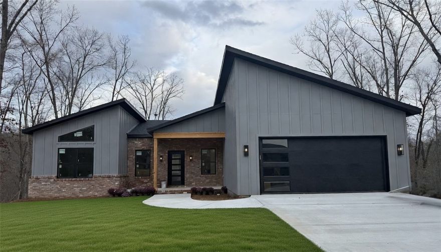 Welcome to this beautiful modern home in Bella Vista! Built by Christopher Hayes Homes, thoughtfully designed new construction 1,858 sq ft, 3 bed, 2 full bath & 2-car attached garage—all on one level. With 10 foot ceilings, desirable split floor plan complimented with an open main living room/kitchen area perfectly customized with a waterfall island, floating shelves, built-ins & 75 inch flatscreen TV; you are ready for entertaining. The beautifully appointed granite countertops, LED lighting, & modern finishes blend style & function. Exceptional primary bath featuring dual showerheads, primary closet with storage shelves all the way to the top of the built-ins, you are sure to feel the quality craftsmanship throughout that add comfort and convenience. Exterior showcases classic brick, board & batten, cedar accent, architectural shingles, a covered, oversized deck, flat backyard, .34 acre lot. Peaceful surroundings while still being minutes from Bella Vista’s golf courses, lakes, biking trails, dining, & shopping.