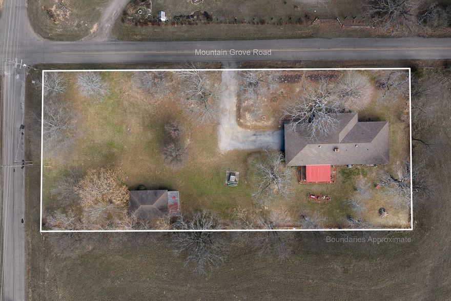 Set on 1.34 acres at the foothills of the Boston Mountain this charming rock home offers space and stunning views. Enjoy a large sunken living room complete with vaulted ceilings, a rock fireplace, Buck Woodstove, & cedar barnyard walls. The kitchen features stainless appliances, a double oven, farmhouse sink & a movable island. Relax on the new redwood-colored composite deck or the stenciled front porch surrounded by mature oaks, maples & fruit trees. The primary suite offers an ensuite, double closets & sliding doors to enjoy the backyard sunsets. Highlights include: Anderson windows & 2 sliding doors (installed in 2020), luxury vinyl flooring in the living room & kitchen & a large utility/laundry room with extra storage. Outside, find a chip & seal driveway, 2-car garage & a large workshop with a roll-up garage door & carport.  This property perfectly blends rugged mountain character with modern efficiency & serene natural views. Don't miss the chance to make it yours!