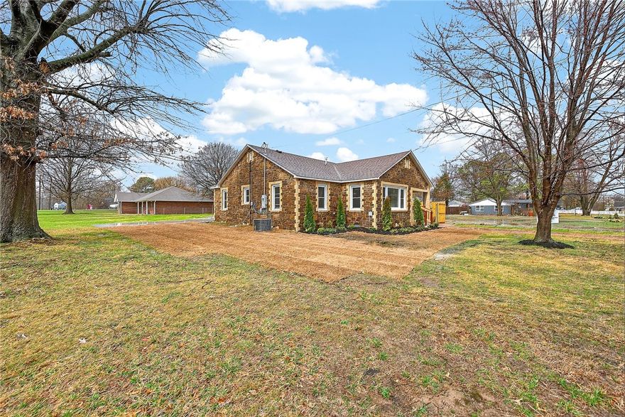 A 1945 stone-masonry charmer reimagined for modern day living filled with warmth & natural light.  Nothing cookie cutter about this cutie! The open floorplan lends itself to family gatherings & memorable holidays. The all-new kitchen features 3cm quartz countertops, new GE appliances & a roomy pantry. You're sure to love the custom bathroom with its double vanity, quartz counter, separate water closet & charming mosaic tilework not found in today's new-builds. The primary bedroom features a light filled walk-in closet. This nearly new home not only boasts NEW hardware, lighting, and paint, but it has been taken down to the studs and floor joists. Joists & subflooring replaced where needed, all NEW wiring & plumbing, NEW drywall, NEW doors, all NEW appliances and cabinetry! NEW waterproof hybrid flooring and tile throughout-NO CARPET! NEW driveway, walkway & privacy fence along the property line! Professional landscaping adds to the curb appeal. Convenient to schools, Northwest Medical, I-49 & downtown Springdale!