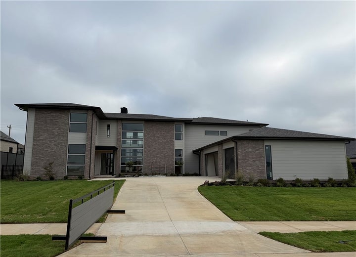 View of front of home featuring brick siding, a carport, a front yard, and driveway