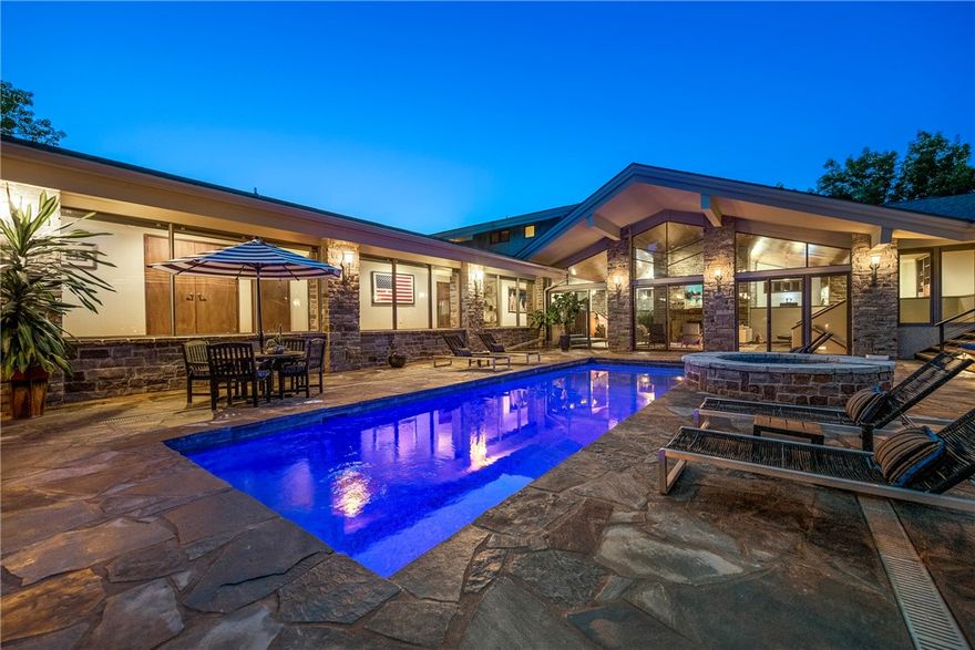 Incredible Prairie-Style Frank Lloyd Wright inspired custom home with amazing backyard oasis. This architecturally significant home stays true to form; unassuming on the front, blending into Mother Nature with massive walls of glass overlooking the flagstone pool, layers of outdoor space and the manicured grounds. True FLW style all the way, even down to the "salute to wheat" hidden in the cathedral glass window of the great room. This home has a vibe like no other, perfect for entertaining or simply relaxing. Life seamlessly flows from indoor to outdoor space. There are so many great nooks and crannies to explore. The current owners have just completed a massive overhaul of the outdoor space. It includes an alfresco dining area with a 20'x8' natural edge pecan table with fire feature. Imagine the memories that can me made around this marvelous table. Inside you will love how the house flows.  Several smart home features including whole home lighting and audio. This is a home made to enjoy life.