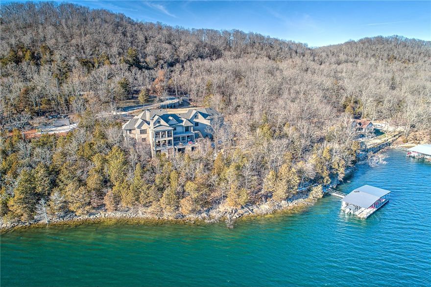 This is Beaver Lake luxury at its best. At over 7000 sq ft, this incredible home sits lakefront on three pristine acres near lost Bridge Marina. Spectacular views abound from three levels all throughout the home. The property boasts upgrades galore including a technologically advanced smart-home hub, a roof designed to withstand winds in excess of 130 mph, an outdoor kitchen complete with wine fridge, wood smoker and oversized grill, not to mention a multitude of other luxury amenities too numerous to detail here. Comfortable, yet refined, the home flows seamlessly from one room to the next and into the outdoors where one can enjoy a landscaped trail that leads to a scenic overlook centered around a custom firepit/patio area. There is even a private boat dock with slips for boats and jet skis. Needless to say, this residence has it all.  Experience the very best of Northwest Arkansas living today at 22007 Pine Log Rd.