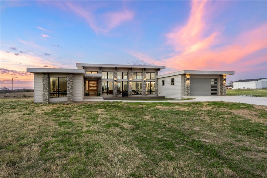 Experience refined open-concept living in this stunning modern home set on just under 10 acres, offering the perfect blend of contemporary design, comfort, &  peaceful privacy. Flooded with natural light, the airy layout seamlessly connects the main living, dining, & kitchen spaces, creating an ideal setting for everyday living & entertaining. The gourmet kitchen serves as the heart of the home with premium Bosch appliances, sleek modern finishes, & generous gathering space.

Enjoy effortless indoor-outdoor living with an inviting front patio & expansive covered back deck overlooking the surrounding landscape. The luxurious primary suite feels like a private spa retreat, featuring a state-of-the-art walk-in shower & oversized two-person soaking tub.

Flexible bonus space offers endless options for a home office, media room, playroom, or creative studio, while the large metal workshop provides space for hobbies, equipment, or storage. Modern style, open spaces, and room to breathe—this property truly has it all.