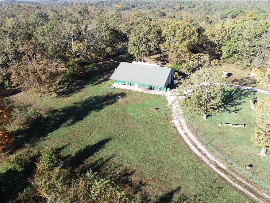 Experience ultimate peace and tranquility just a 35 minute drive from Downtown Bentonville with this rare 61-acre offering. The custom shop features comfortable living quarters seamlessly connected to a large, attached shop, providing ideal utility for projects or storage. Set on 19 acres, the property offers plenty of deer for hunting opportunities and incredible potential for opening up commanding views of the rolling Ozark hills. The expansive land includes multiple homebuilding sites for an additional residence of future development. This unique property combines modern functionality with an expansive, private landscape, perfect for those seeking country living with quick city access.