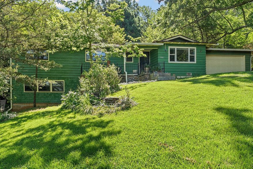 Fantastic price improvement on this Mount Sequoyah home walking distance to Root Elementary, but still private and peaceful with deer grazing and flowers blooming year-round in large backyard. This lovely “Craftsman” family home sits on half-acre lot backing to a forest, but no worries--new gutters have leaf guards! On entry you are greeted by a big, warm, inviting living room with new Pella picture window that overlooks the forested hills below. Continue to the kitchen and dining room, each with new Pella sliding glass doors to back patio and yard. Main level features a primary bedroom with new carpet and an ensuite. Three more bedrooms and a bathroom on main level before heading downstairs for family game night in the giant great room with built-in fireplace, lots of windows and a flex space. Some new and fairly new carpet, hardwoods or new laminate floors cover the entire home. The entire interior and exterior are newly painted. Lots of storage in the crawlspace, indoor storage room, and two-car walk-in garage.