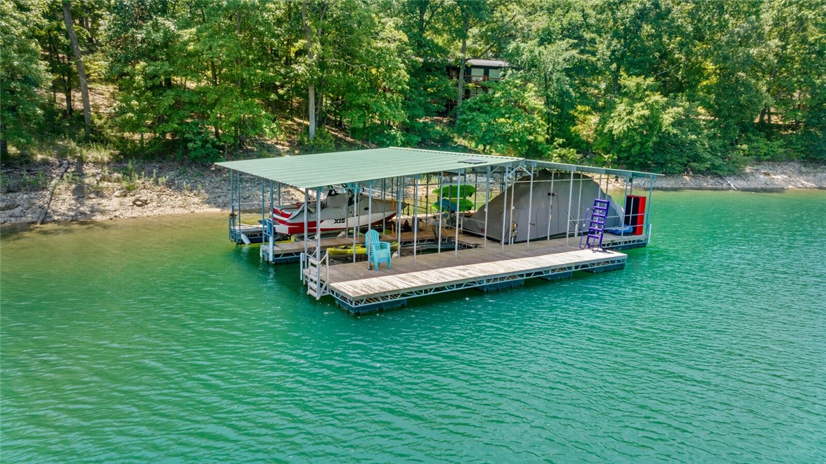 Experience Beaver Lake living with an easy walk to two boat slips in a 2 owner dock. This cabin has ample sleeping spaces and a beautiful outdoor deck area nestled among large trees. The open living, dining and kitchen areas are bright with natural light from the wall of windows. Take the short walk down the path from the house to enjoy your 10' x 26' boat slips and the clear waters of Beaver Lake! The upper level includes the living room, kitchen, utility, 2 bedrooms and 2 baths. The lower level includes a family room and an additional bedroom. Only 40 minutes to the new Walmart headquarters in Bentonville and all NWA has to offer!