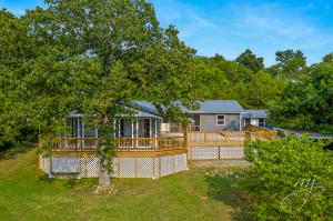 Imagine relaxing after work, or entertaining friends and family on this new 34' x 22' deck! And, a screened porch allows you to enjoy the outdoors year-round. Gorgeous windows lead the way into the amazing 23' x 13' sunroom. New upgrades include: metal roof, flooring, siding, paint, windows, electrical panel, hot water tank--- and the list goes on and on. Four bedrooms and 2 1/2 baths, a family room, living room, office/homework room and sitting room offer lots of space for a growing family. Office could also be used as a 5th bedroom. Workshop/storage building just steps away from the back door. A storm shelter/unfinished basement storage area is accessible from the front of the house.