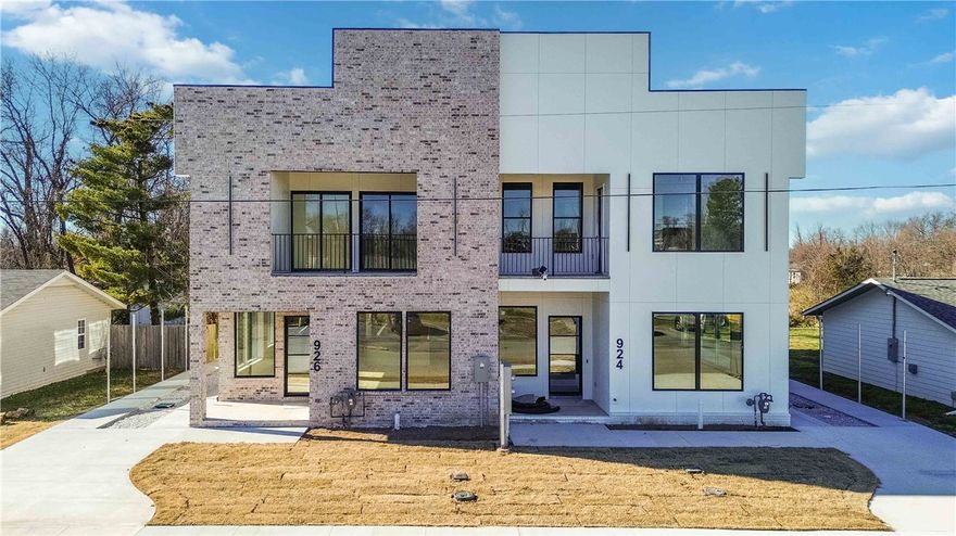 Welcome to effortless modern living in the heart of Bentonville. This newly constructed townhouse showcases exceptional craftsmanship and thoughtful design, offering four spacious bedrooms and 3.5 bathrooms—including two primary suites that provide flexibility for co-living, guests, or multi-generational living. The gourmet kitchen features high-end appliances that will delight any home chef, while an additional kitchenette adds convenience and versatility. The open-concept layout is bathed in natural light from generous windows, creating a warm and inviting atmosphere. Step outside to a large covered patio perfect for relaxing or entertaining, rain or shine. Located within walking distance to 8th Street Market, Thaden School, and the Walmart Home Office Campus, this home places you at the center of Bentonville’s vibrant community. From premium finishes to a smart floor plan, every detail reflects quality and comfort. If you’re seeking space, style, and location, this one checks all the boxes.