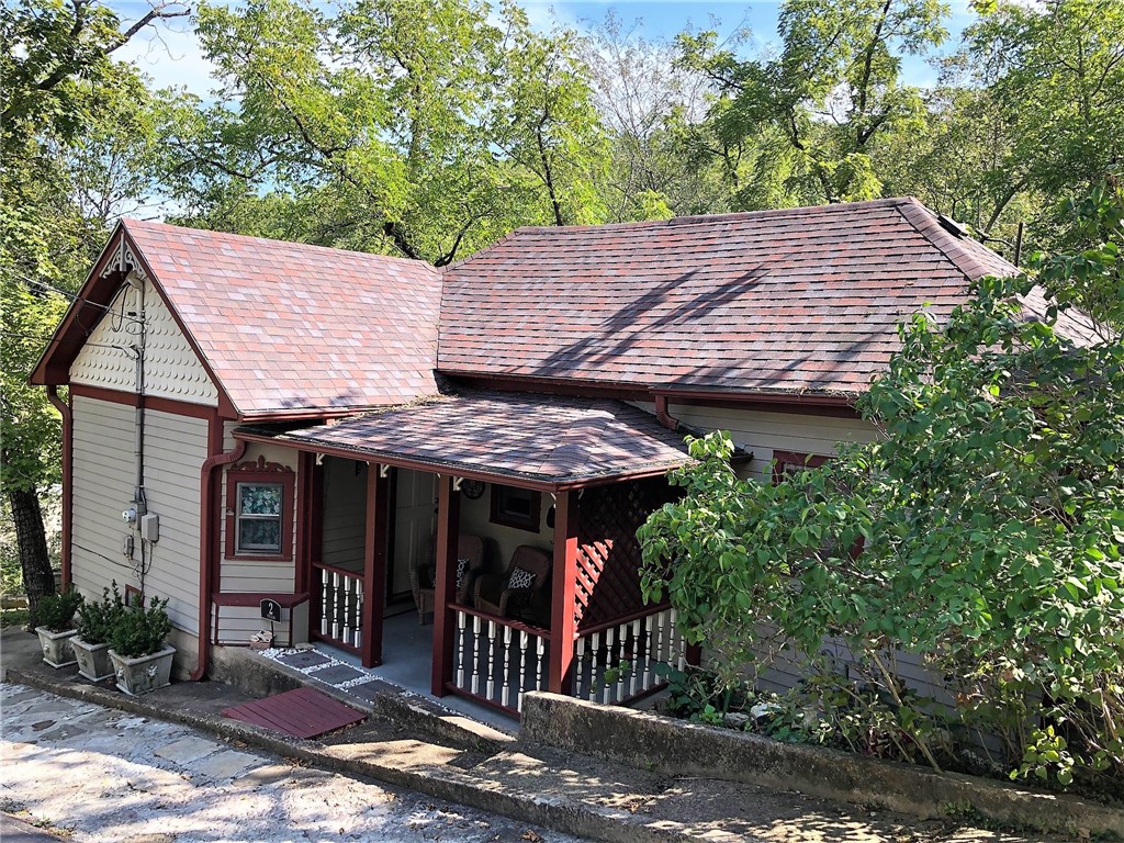 You'll love this remodeled 2BR/2BA cottage with vaulted open-beam ceiling, vintage wood floors and unique architectural details. Spacious kitchen with quartz counters and living room is open concept for easy entertaining. The master bedroom is on the main level and a guest bedroom is on the lower level with a private entrance that opens onto the wrap around deck. One bath has a shower and the second has a vintage porcelain tub/shower from a historic Eureka Springs hotel. Two spacious walk-in closets have shelving. The utility room is conveniently located off the kitchen. A large workshop with concrete floors is on the ground level along with a separate storage room with concrete floors. Wonderful back deck overlooks a wet-weather creek that flows from Little Lake Eureka. Great neighborhood for walking with beautiful rock bluffs, several springs, and architecturally interesting homes. Off-street parking for two to three cars. Easy walk to your favorite downtown shops, galleries and restaurants