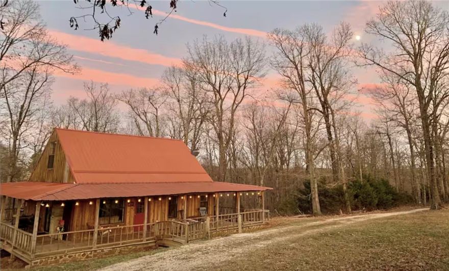 Firefly Cottage is  a well-established, fully-furnished nightly rental cabin located in Mt. Sherman in the heart of the Upper Buffalo River Wilderness area, less than 3.5 miles to Kyle's Landing & Horseshoe Canyon Ranch. The cabin sits on 11 private acres at the end of a dead-end road, surrounded by pasture with regular visits from horses, cows, deer, black bear and turkey!
The spacious Primary Bedroom sits on the main floor with a large bathroom including a soaker tub and separate shower. A sleeping loft outfitted with three twin beds is just upstairs. One of the favorite features of the cabin is the covered wrap-around porch that spans all four sides of the home, including a screened porch at the back that is perfect for dinner al fresco.
A second septic system is installed on-site, offering Buyers the option of creating an additional income-producing opportunity! The site is perfect for a "Marfa"-style camper community by revising the existing structure into a bath house.