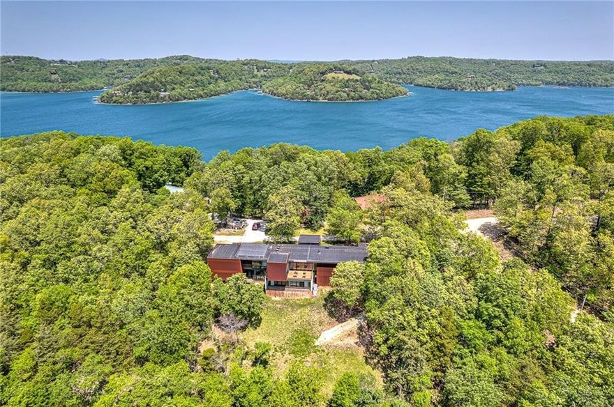 CUSTOM BUILT AND DESIGNED CONTEMPORARY MASTERPIECE TUCKED AWAY ON A 1.48 ACRE PARTIALLY WOODED LOT BOASTING SPECTACULAR OPEN VIEWS OF BEAVER LAKE! One slip in the community boat dock nearby! Private pool room w/ indoor heated swim spa, hot tub & bath!  This unique property was built & designed to be energy efficient and low maintenance with a metal exterior and floor to ceiling commercial grade windows and sliders throughout that fill this work of art with natural light and bring the outdoors inside! The main level hosts a sleek & functional chef’s kitchen, formal dining, media room/study w/ built-ins, screened deck w/ outdoor kitchen, a living area w/ dual sided fireplace, built-ins w/ wet bar & an exceptional lake view!  Main level primary suite also enjoys floor to ceiling windows w/ amazing views and a luxurious en suite bath w/ walk-in closet! Lower level features 2 bedrooms each w/ a private en suite bath, large unfinished bonus/hobby room/4th bedroom. Fabulous outdoor living spaces! Large workshop w/ view!