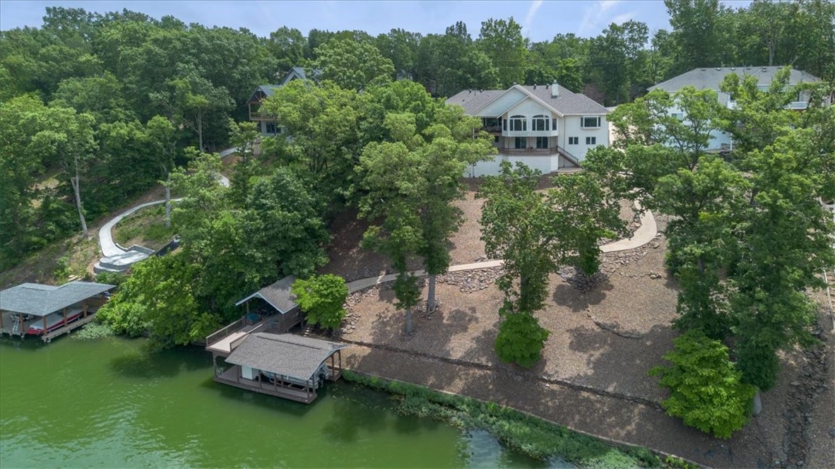 Private lakefront oasis with 131' of shoreline. This home offers stunning sunset views, abundant space, & direct access to some of the best fishing. Step into an expansive kitchen with an oversized island, ideal for gatherings. The open-concept flows seamlessly into the living room & 350 sqft sunroom—perfect for coffee/relaxing with a book. A dedicated office provides a quiet retreat. Primary suite features lake views, walk-in shower, oversized whirlpool tub, & his-and-hers walk-in closets for top convenience. Downstairs, has 2 bedrooms, 2 bathrooms, kitchenette, & 2nd living area—complete with a pool table that conveys. Plus, 750+ sqft of unfinished space for storage/future expansion. 2 composite decks overlooking the lake. A fenced dog yard off the side of the home. Your private dock features 900 sqft of entertaining space, shuffleboard/dining table combo that conveys. Lower deck includes a covered boat dock with lift. New roof installed April 2025. Three-car oversized garage. Boat & side-by-side negotiable