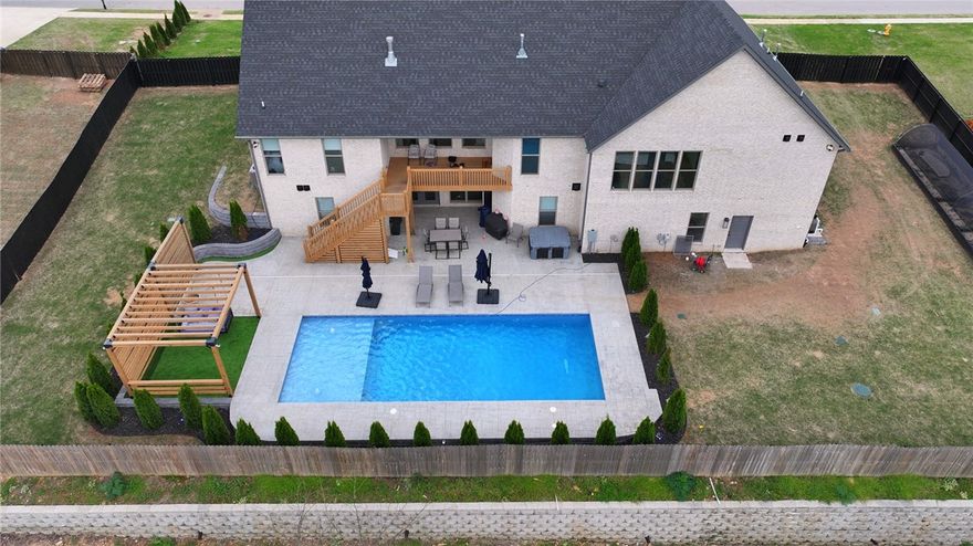 Located on over half an acre near Lake Elmdale, this 5-bedroom, 4-bath home is part of a neighborhood of 32 homes with convenient access to Interstate 49 just minutes away. Built in 2022, the property offers over 5,500 square feet of living space, including an approximately 700-square-foot addition to the basement. The main level includes a kitchen with a built-in refrigerator, double ovens, a large island, and hardwood flooring. The home is positioned to capture north-facing views over surrounding green valleys. The walk-out basement provides additional living space and includes a secondary kitchen area, offering flexibility for a variety of uses. Exterior features include a modern-designed pool, full irrigation system, and permanently installed exterior lighting.