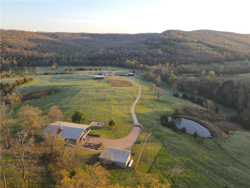 This one of a kind property has everything to offer. Upon entering through the gate, you are greeted with expansive pastures and stunning landscape. A metal shop sits at the front of the property featuring a 4 bed, 2.5 bath addition. Next to the metal building there is a fully operational cattle corral. As you pull up the driveway, you will notice the multiple out buildings and an equestrian barn equipped with stalls and tack room. The driveway continues up the gradual hillside to the main 3,789 Sq.Ft. home which has 6 beds, 4.5 baths. This home is 80% handicap accessible and has proven successful as a nightly rental. From the front porch you are able to enjoy breathtaking views of the surrounding landscape. With trails expanding to almost every corner of the property, you are able to make
your way through the forest with ease. A notable feature is a beautiful cave near the edge of one of the creeks. Following the creek up the mountain, you will come across a spring that is nothing short of impressive.