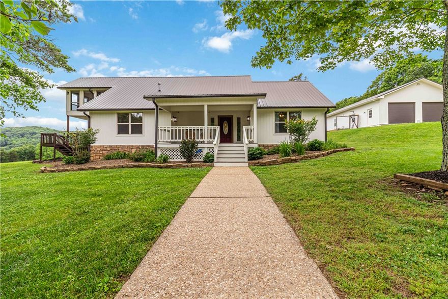 Just 20 minutes from the University of Arkansas, this stunning 87.76-acre Ozark property offers updated, move-in-ready living without sacrificing space, privacy, or scenery. The 5-bed, 3-bath main home features wood floors, a remodeled kitchen with butcher block island and stainless appliances, two living areas, and four bedrooms on the main level. Upstairs, the primary suite includes a redesigned bath, walk-in shower, and a private all-season room opening to an upper deck with sweeping mountain views. The newly replaced back deck overlooks lush pasture, five ponds, and legendary Ozark night skies. The detached 2-car garage includes a fully equipped 2-bed, 1-bath apartment (966 sq ft, not included in main home total) with covered porch, full kitchen, laundry hookup, new metal roof, and fresh paint — perfect for guests, family, or rental income. Homestead, hobby farm, or your own piece of the Natural State — this one checks every box.5k in preferred lender credits