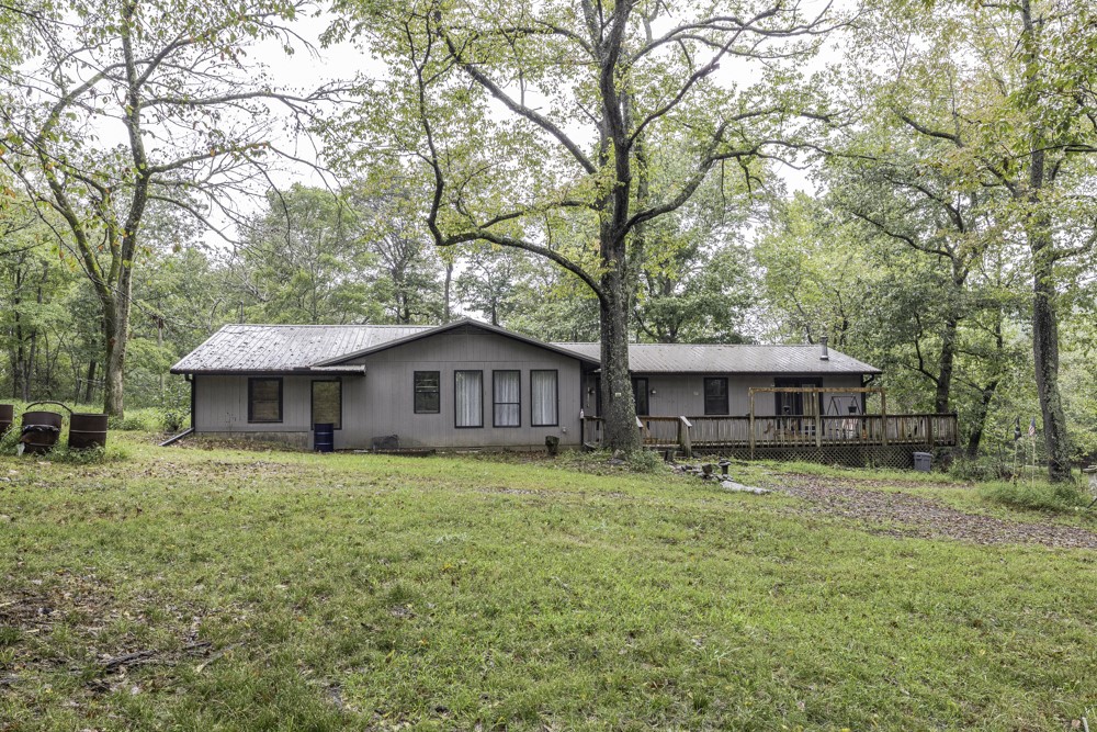 Country living at "Hidden Meadows", this beautiful piece of the Ozarks has privacy, seclusion and lots of nature to enjoy! With the large deck on the front you can sit and relax and watch the sunrise or go down and explore the seasonal creek on the edge of the property. This home has a large living room with a wood stove that gives a rustic, country feel, then the kitchen and dining room make it easy to entertain guests. Windows are argon gas double pane. The work shop and storm cellar provide space for projects and storage Out buildings include: barn, well house, goat shed/small horse stable, pig pen, storm shelter up on the hill behind the barn.
The mature trees provide shade in the summer and beautiful foliage in the fall! Schedule your showing today!