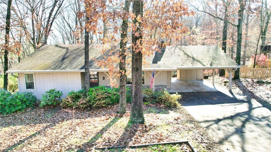 This classic home is situated on a beautiful, wooded lot and offers the perfect balance of peaceful seclusion and quick access to golf, lakes, and the renowned NWA trail system. Enjoy the sunroom and wrap around deck with covered seating area or cozy up to the natural stone fireplace with wood burning insert. Carport has a 220 volt outlet and storage room. The 432 sq. ft. heated/cooled basement (not included in sq. ft. above) with its own private entrance has a full bath and will make a great workshop or hobby room.  This is a prime opportunity for an investor or a buyer looking to make their own updates. Schedule your showing today!