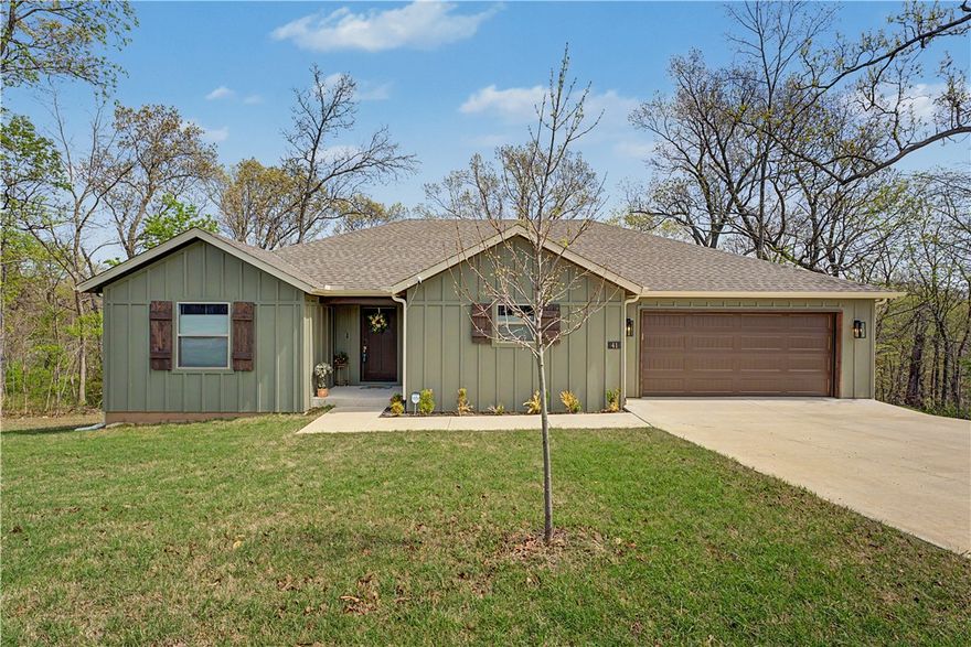 A must see home! Come inside to discover a bright, inviting interior featuring an open-concept living space, abundant natural light, and finishes that create a true sense of home. The kitchen's added island provides additional prep space and a gathering spot for family and friends. Ample cabinetry and a large walk-in pantry/closet has your storage needs covered. Window TDBU blinds throughout the home add privacy and style, not to mention just the right amount of sunlight. Comfortable bedrooms provide restful retreats, with a primary suite designed for relaxation at the end of the day. Step outside to enjoy the covered deck, perfect for morning coffee, evening dinners, or simply relaxing while taking in the peaceful wooded backdrop. This home provides access to many amenities — including golf courses, scenic lakes, walking and biking trails, parks, and recreational facilities. This location offers close proximity to 1 of Bella Vista’s fire departments for peace of mind and easy access to I-49 for your travel needs.